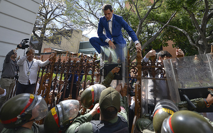 National Assembly President Juan Guaido, Venezuela's opposition leader, climbs the fence in a failed attempt to enter the compound of the Assembly, as he and other opposition lawmakers are blocked from entering a session to elect new Assembly leadership in Caracas, Venezuela, Sunday, Jan. 5, 2020. With Guaido stuck outside, a rival slate headed by lawmaker Luis Parra swore themselves in as leaders of the single-chamber legislature. (AP Photo/Matias Delacroix)