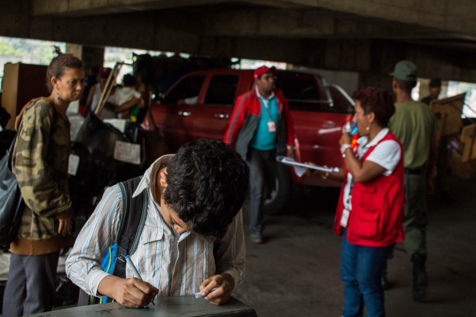 Un niño se entretiene escribiendo en el polvo de un televisor mientras cargan sus pertenencias a una de las camionetas. 