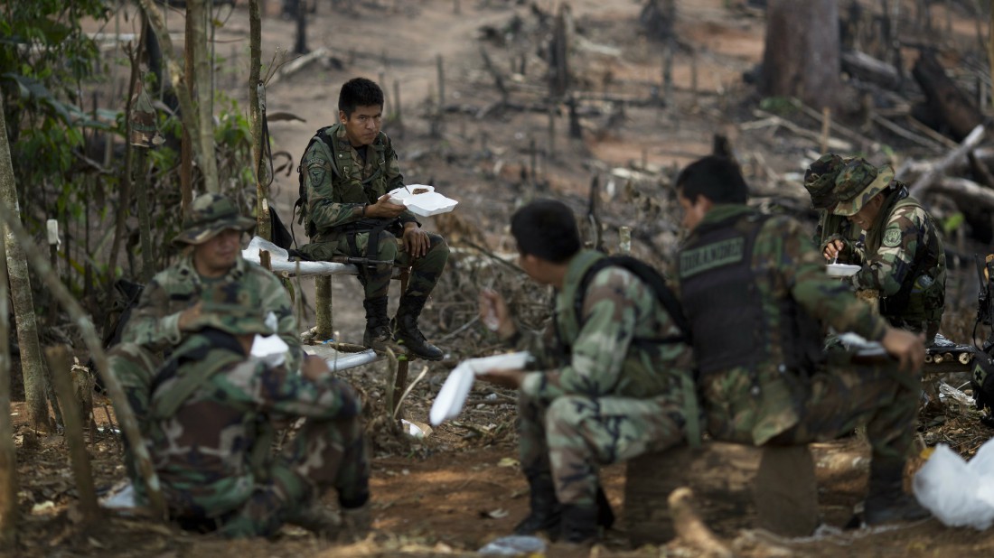 Hombres contratados para brindar seguridad a los "erradicadores" almuerzan en la selva pocos minutos antes de que un helicóptero de Estados Unidos los recoja. Estuvieron 8 días trabajando en una comunidad remota dentro de la selva amazónica de Perú. Foto por Rodrigo Abd.