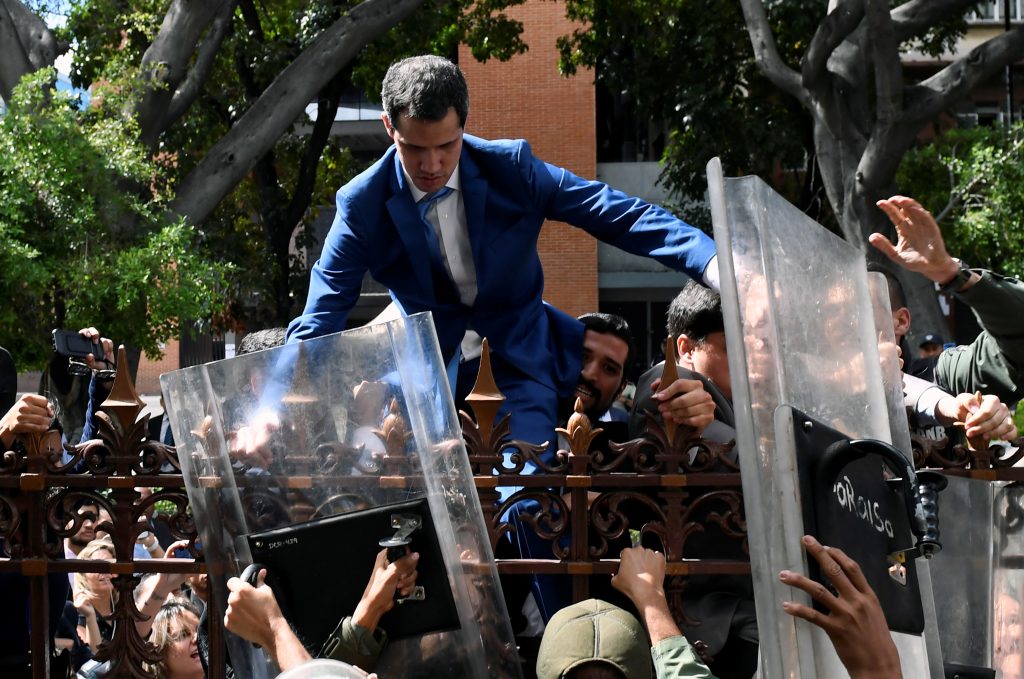 Venezuelan opposition leader and self-proclaimed acting president Juan Guaido is helped to climb a railing in an attempt to reach the National Assembly building in Caracas, on January 5, 2020. - Venezuela's opposition lawmaker Luis Parra -a rival to Juan Guaido- declared himself parliament speaker, as Guaido and fellow opposition lawmakers were blocked from entering the National Assembly. Guaido had been expected to be re-elected parliament speaker but only regime lawmakers and opposition deputies critical of Guaido were allowed to enter the building. (Photo by Federico Parra / AFP)