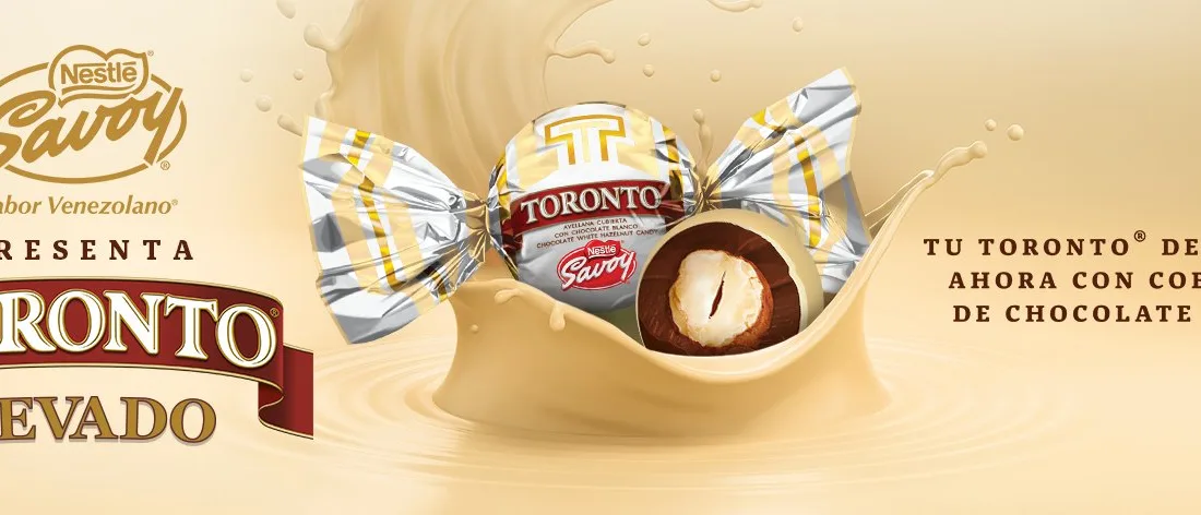 El Toronto Nevado es el tradicional bombón perfectamente esférico y brillante, hecho de chocolate de leche con minitrocitos de frutos secos y al centro una avellana entera, pero con una capa de chocolate blanco que lo envuelve todo.